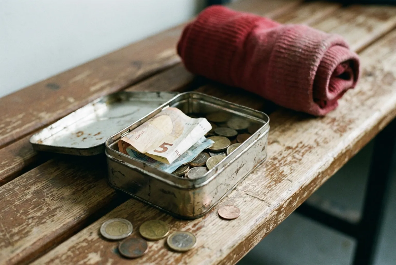 Eine alte Blechdose mit Scheinen und Münzen auf einer Kabinenbank